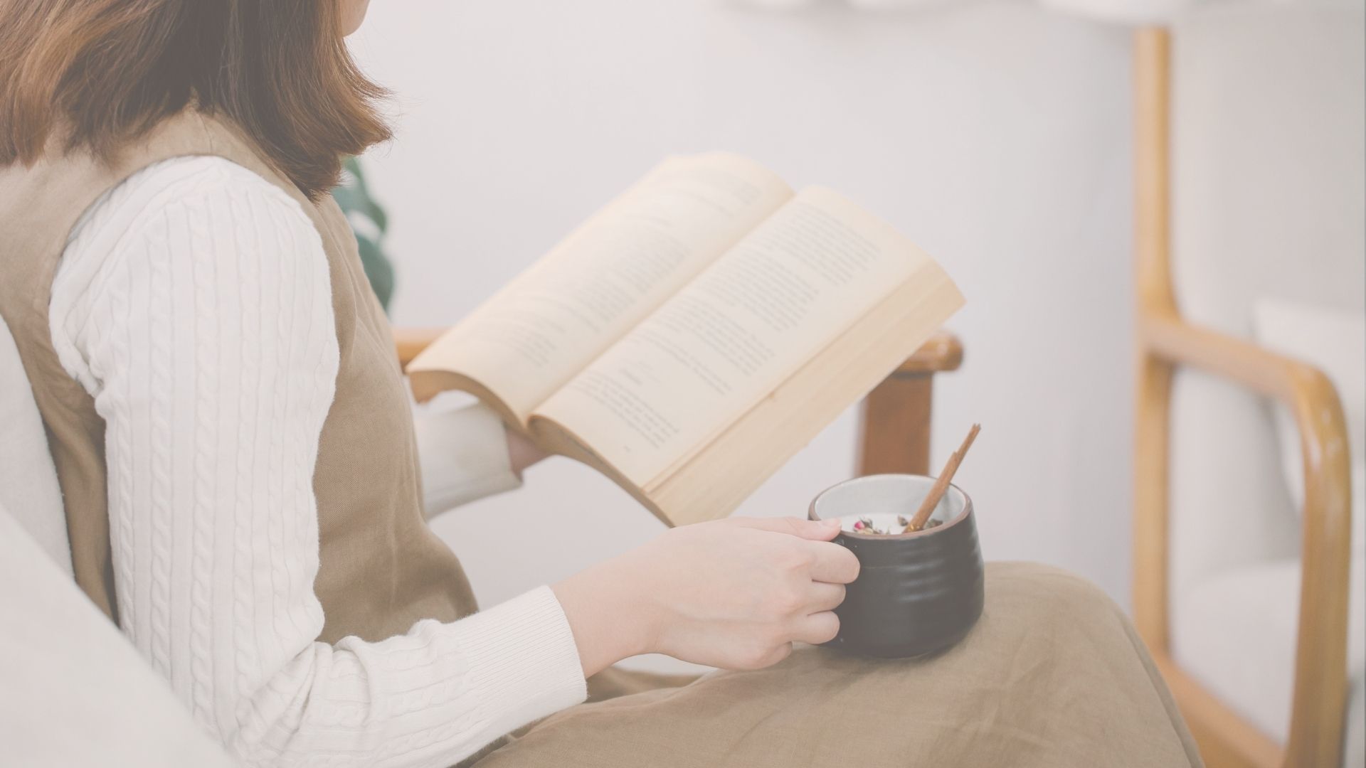 A woman taking a quiet pause with a book and warm drink